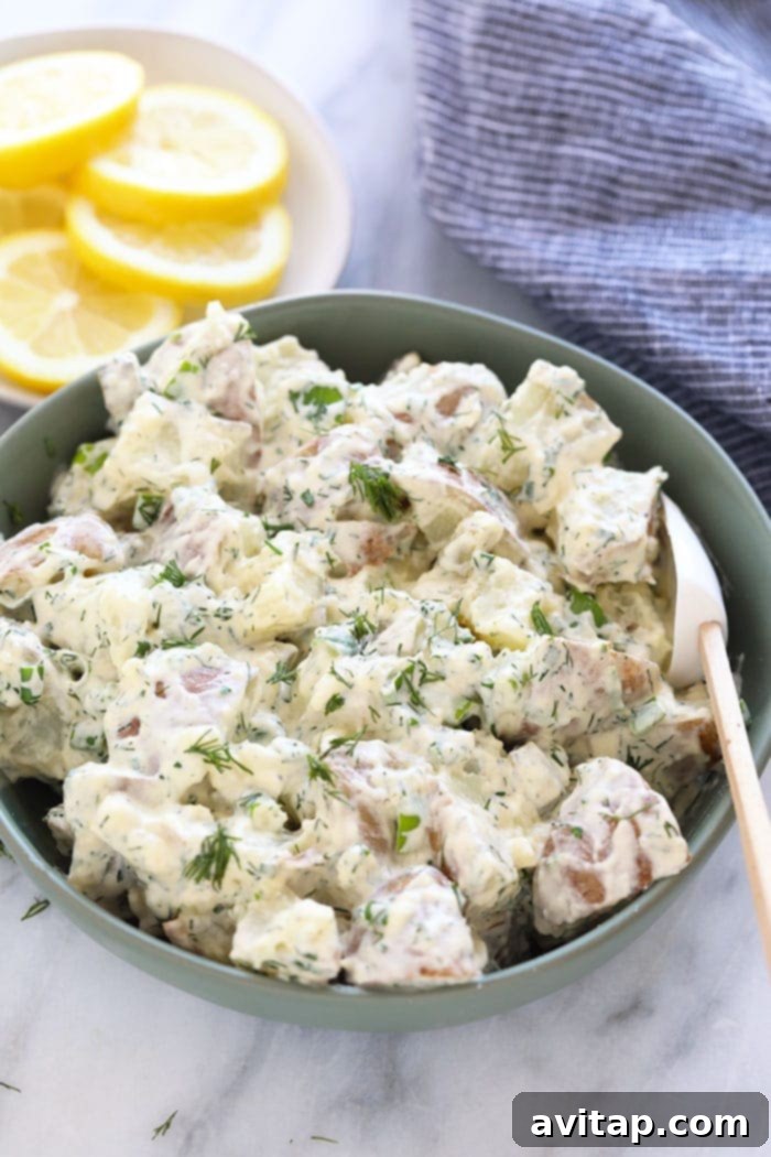 A beautifully presented bowl of creamy vegan potato salad, garnished with fresh herbs, ready to be served.