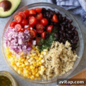 A photo of colorful quinoa salad ingredients, including black beans, red onion, and various chopped vegetables, ready to be mixed into a vibrant salad.
