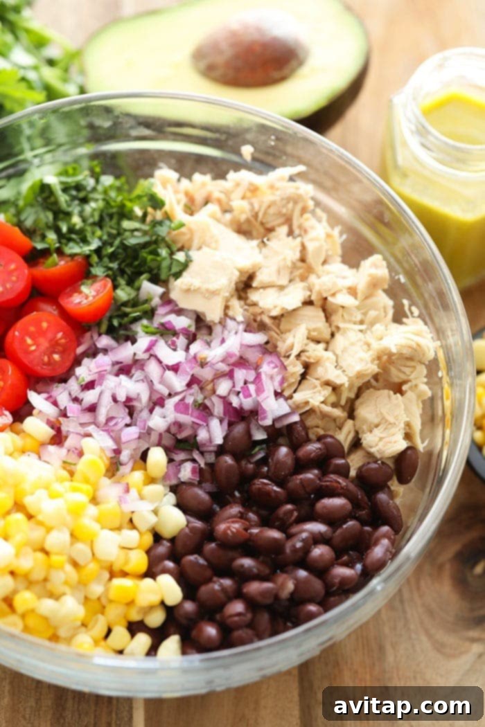 A vibrant Mexican Tuna Salad in a bowl with tortilla chips, showcasing fresh ingredients like corn, black beans, tomatoes, and cilantro.