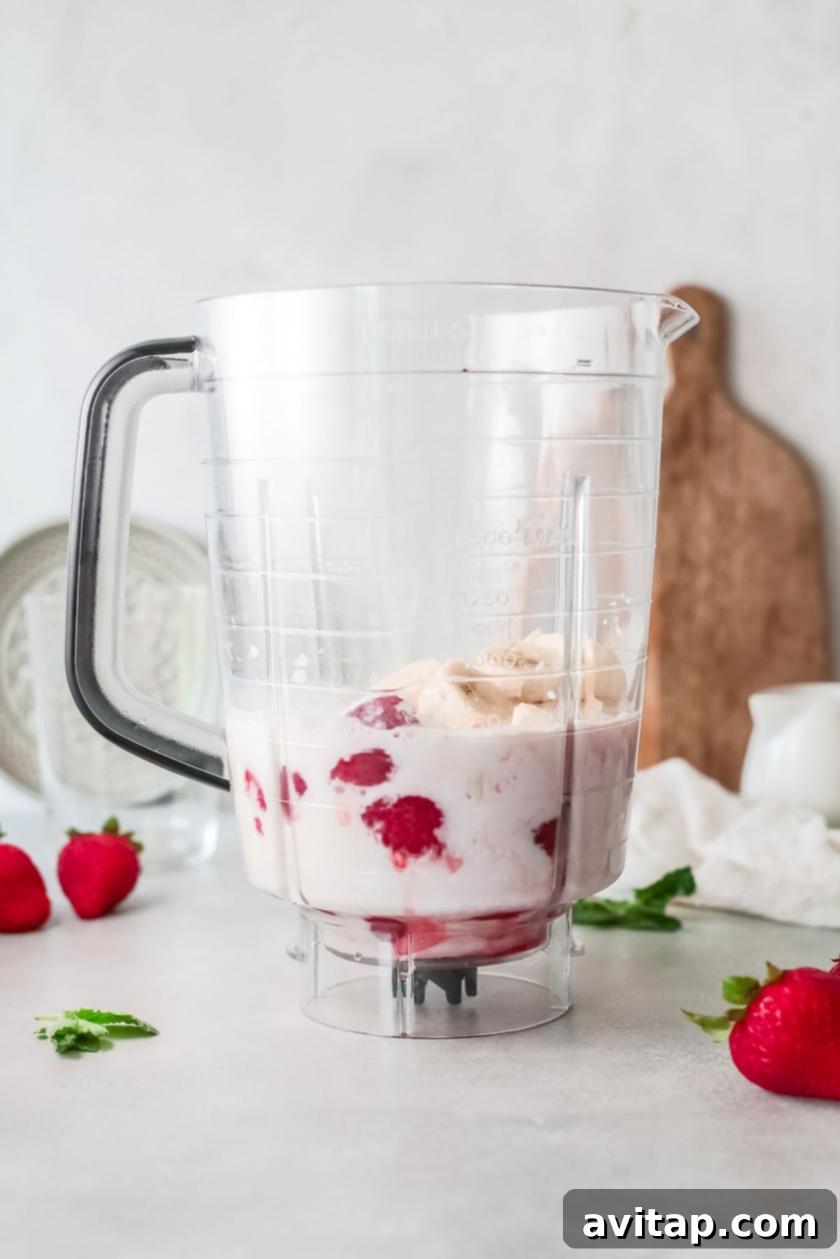 A high-speed blender filled with all the ingredients for a strawberry banana smoothie, ready to be blended into a smooth and creamy consistency.