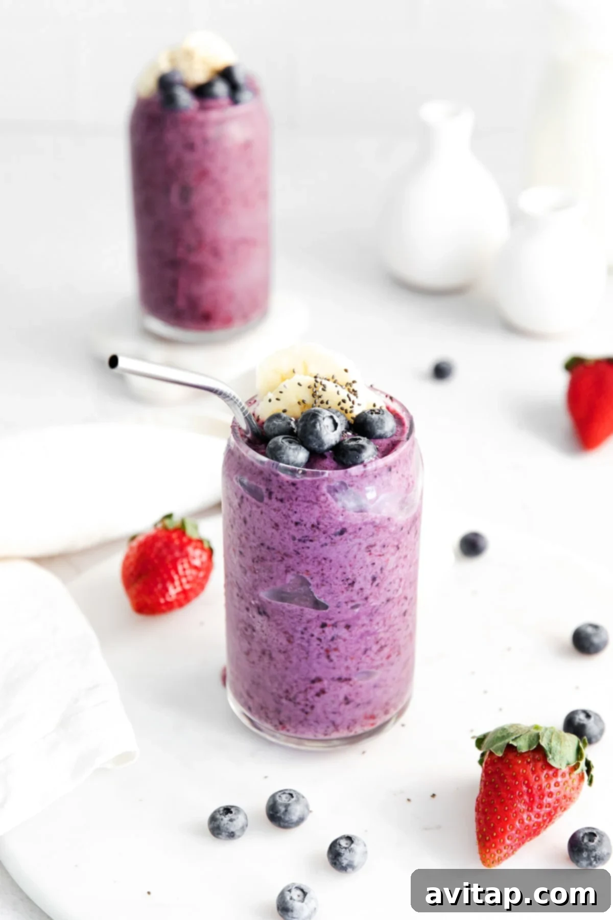 A beautifully presented triple berry protein smoothie in a glass, topped with fresh blueberries, ready to be enjoyed.