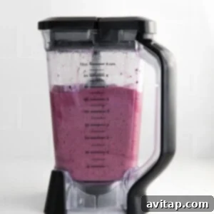 A blender filled with a vibrant blueberry smoothie mixture, ready for blending.