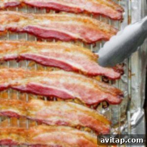 Crispy oven-baked bacon on a wire rack, with a fork gently lifting a piece.