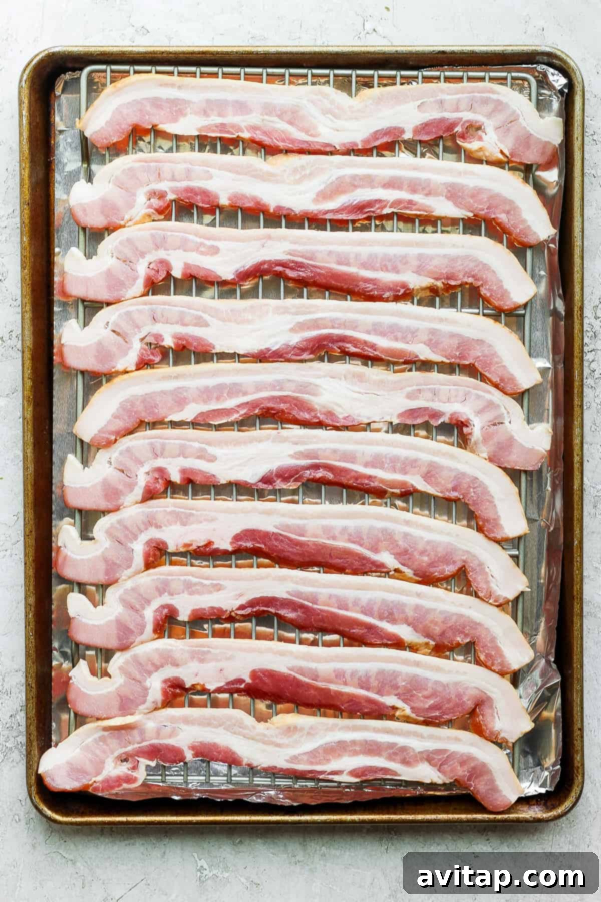 Perfectly cooked bacon strips on a baking sheet with a wire rack, illustrating the even cooking.
