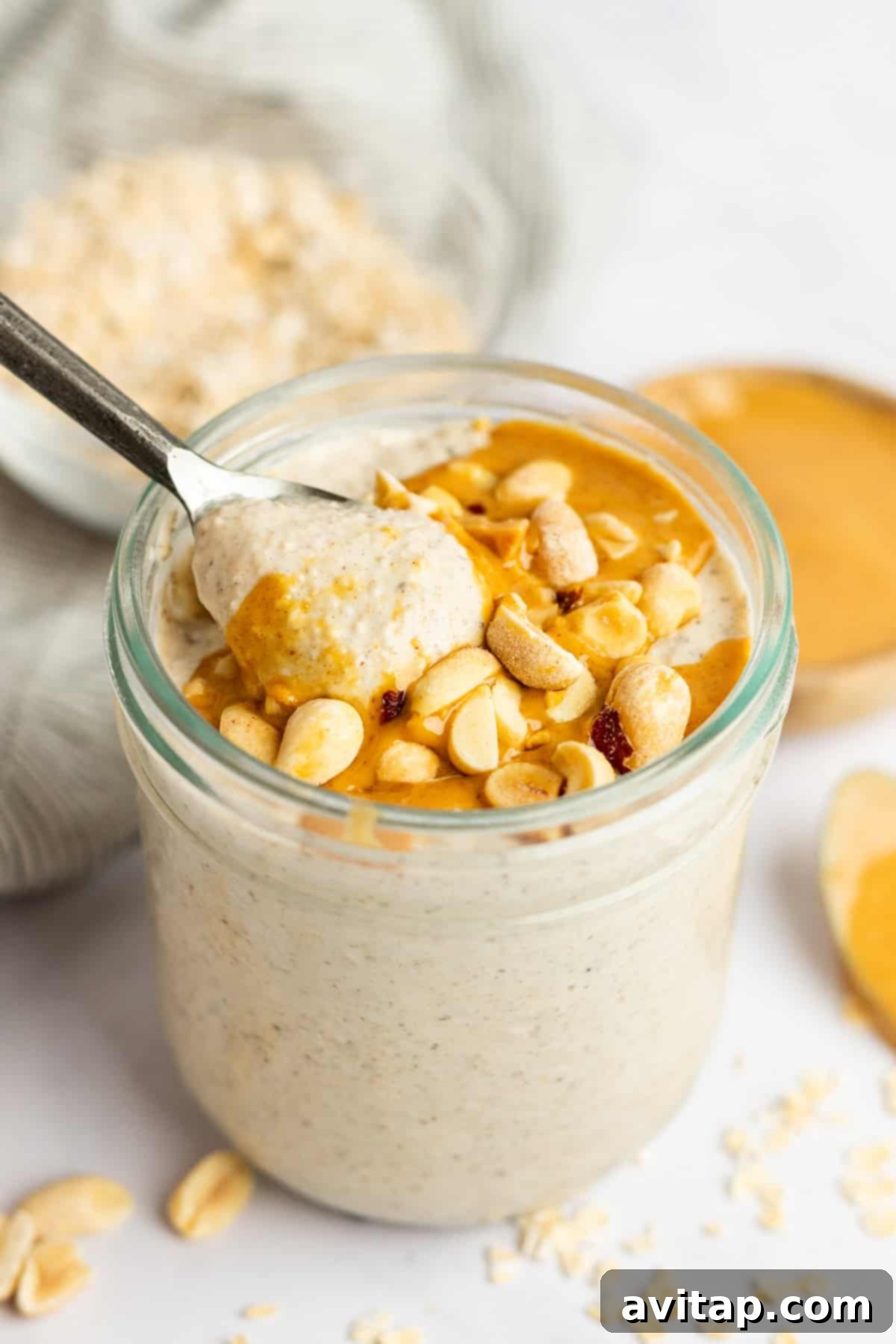 A beautifully styled jar of Peanut Butter Overnight Oats, garnished with extra peanut butter drizzle and perhaps some chocolate chips, ready to eat.