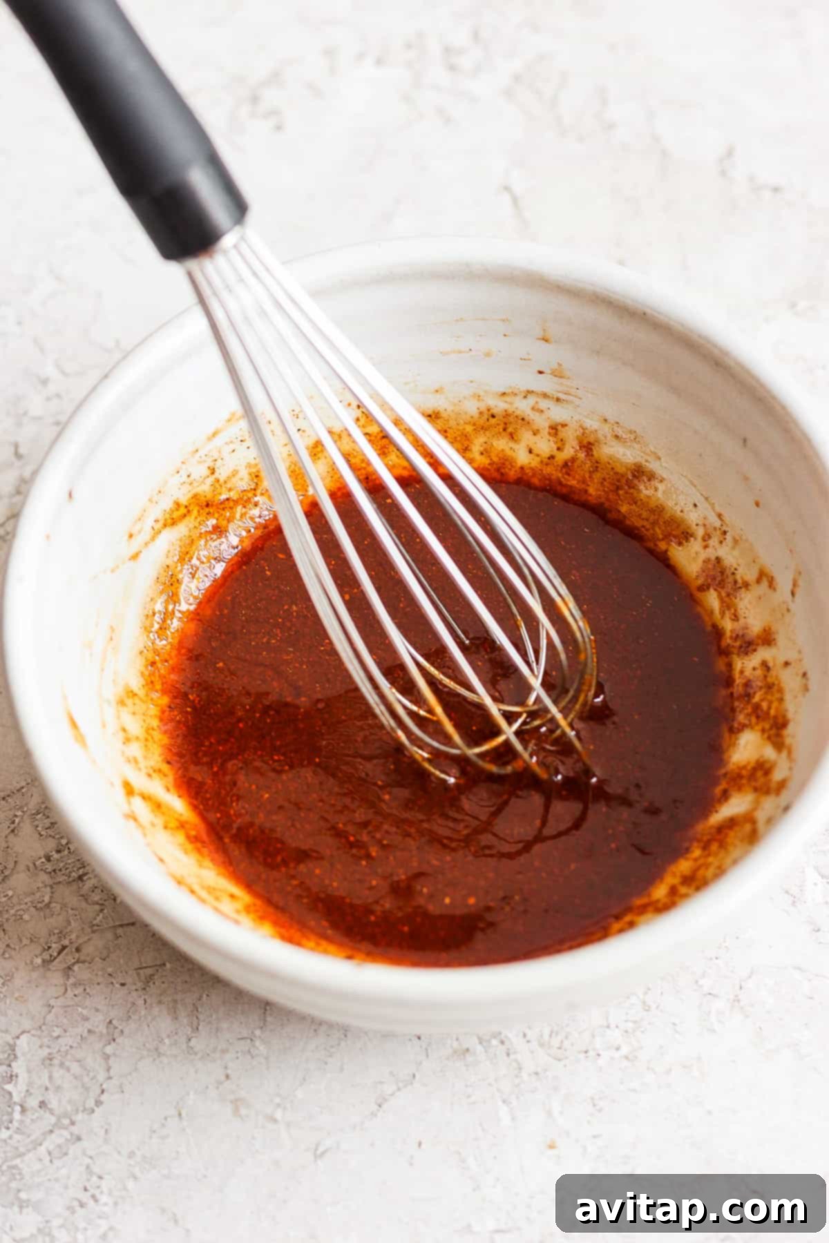 Smoky BBQ Chicken Perfection 3 A bowl of red BBQ sauce with a whisk in it, ready for marinating.