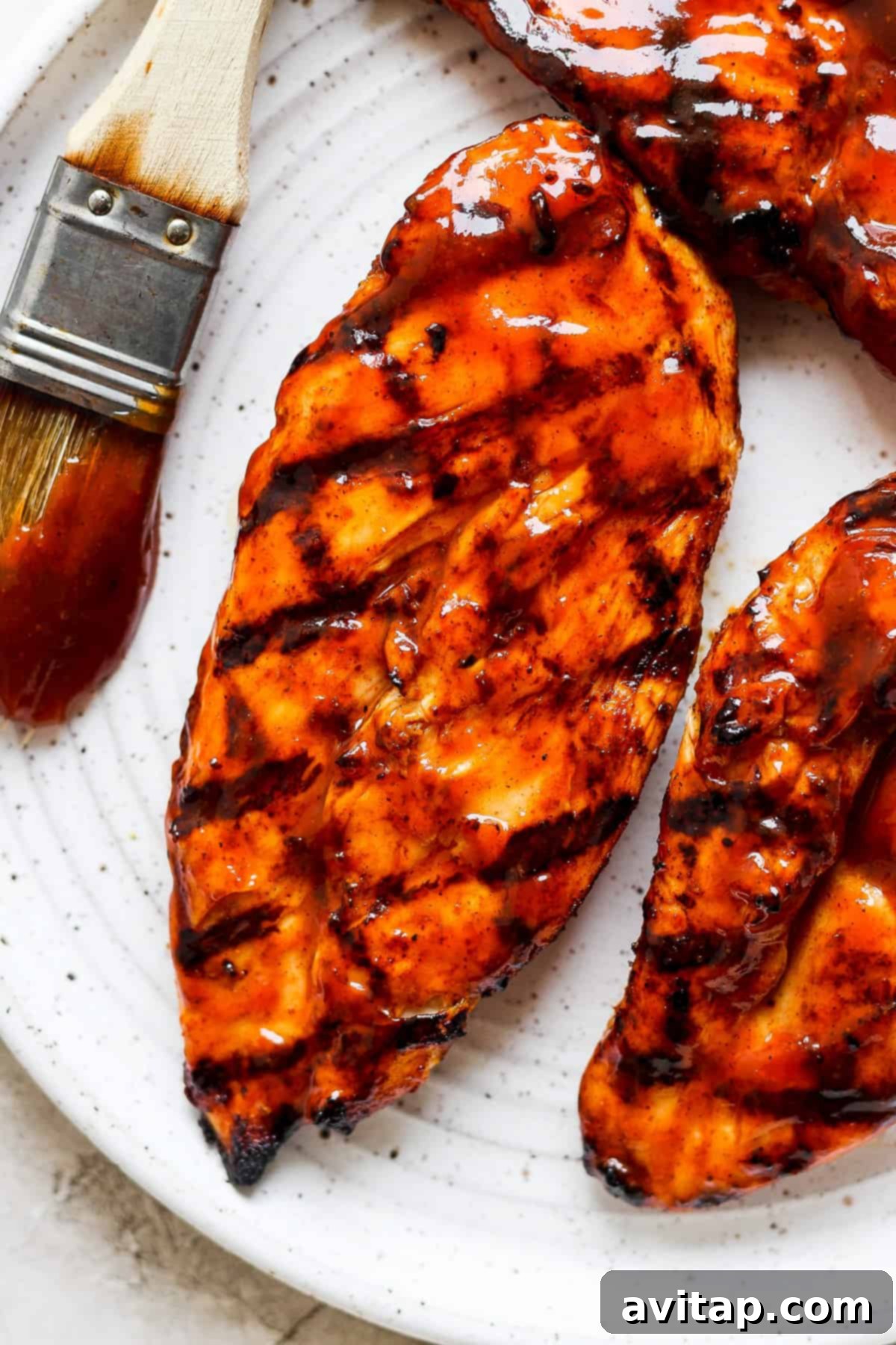 Smoky BBQ Chicken Perfection 6 Grilled BBQ chicken on a white plate with a basting brush and extra sauce.