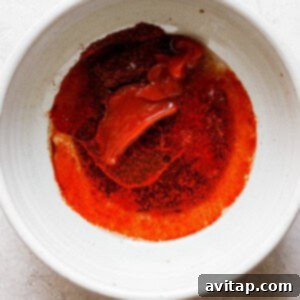 A white bowl with a red sauce in it, the prepared marinade.