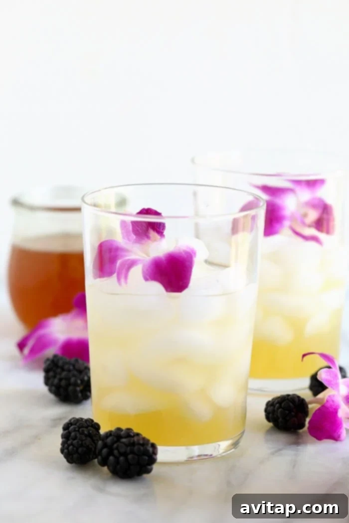 A tall, clear glass filled with glistening ice cubes and a generous pour of homemade lemonade, awaiting the addition of the vibrant hibiscus tea. The scene suggests the initial steps of creating a refreshing Hibiscus Arnold Palmer.