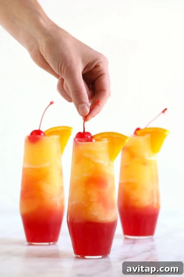 Refreshing Sex on the Beach Slushies served in elegant glasses with a hand holding one, set against a bright outdoor background.