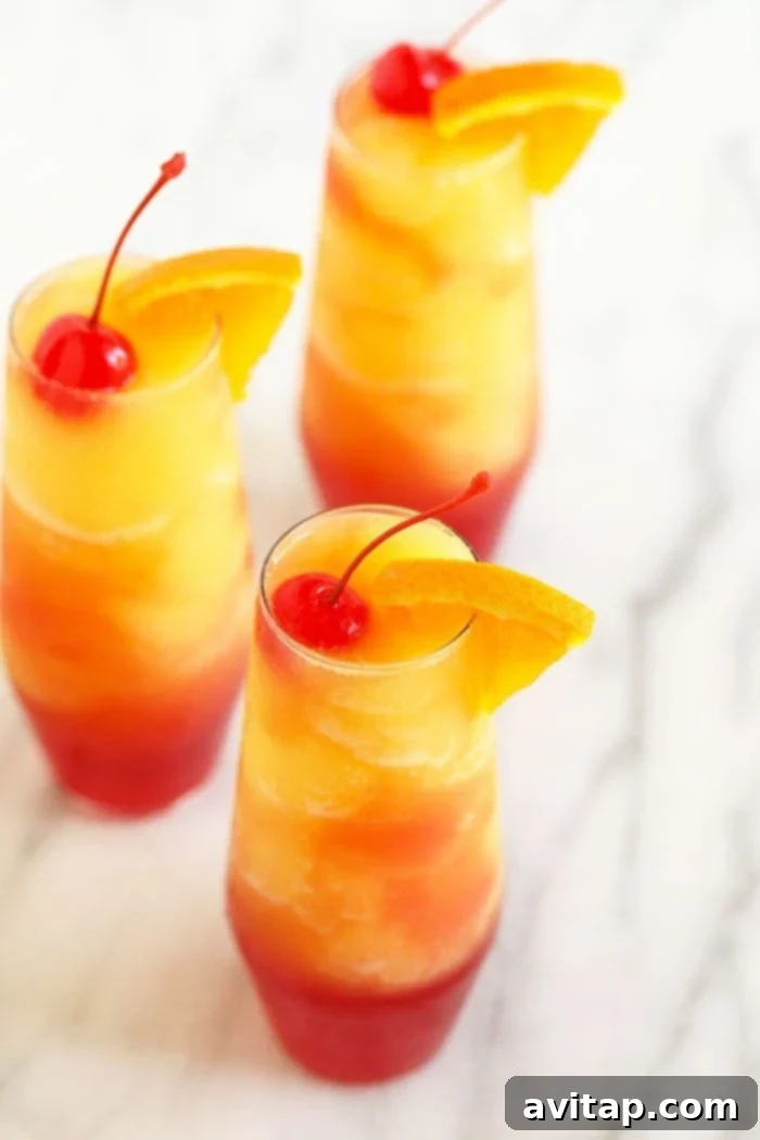 Three perfectly garnished Sex on the Beach Slushies, featuring orange slices and maraschino cherries, presented in tall elegant glasses.