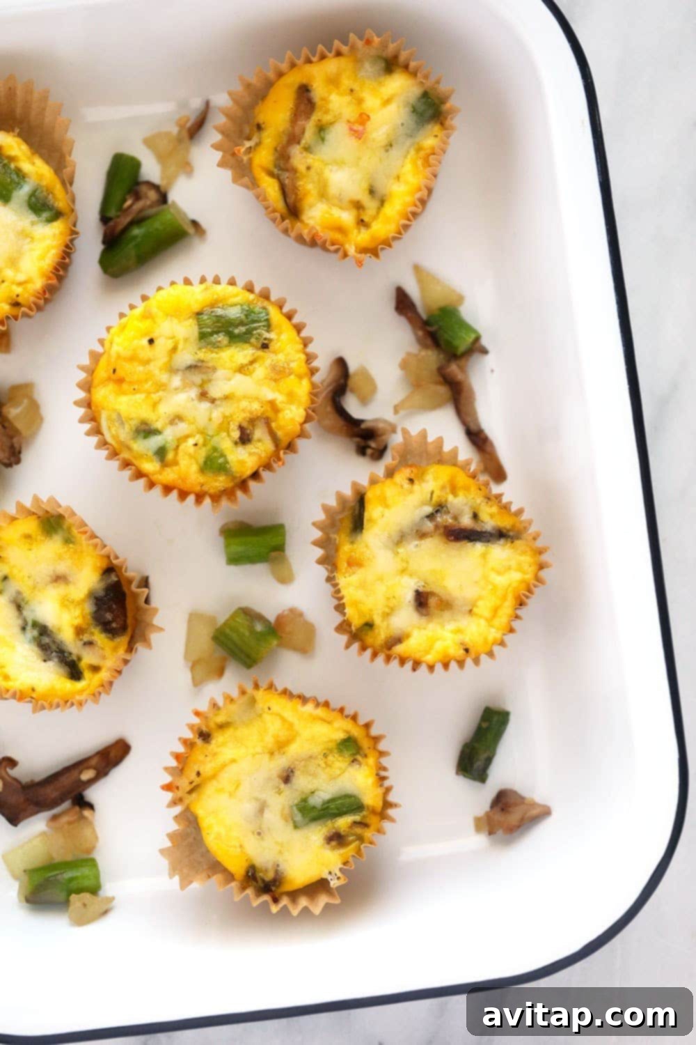 Start your day right with these healthy, protein-rich asparagus and mushroom egg cups, prepared in under 30 minutes! Healthy asparagus and mushroom egg cups arranged in a pan, showcasing their golden-brown tops and vibrant fillings.