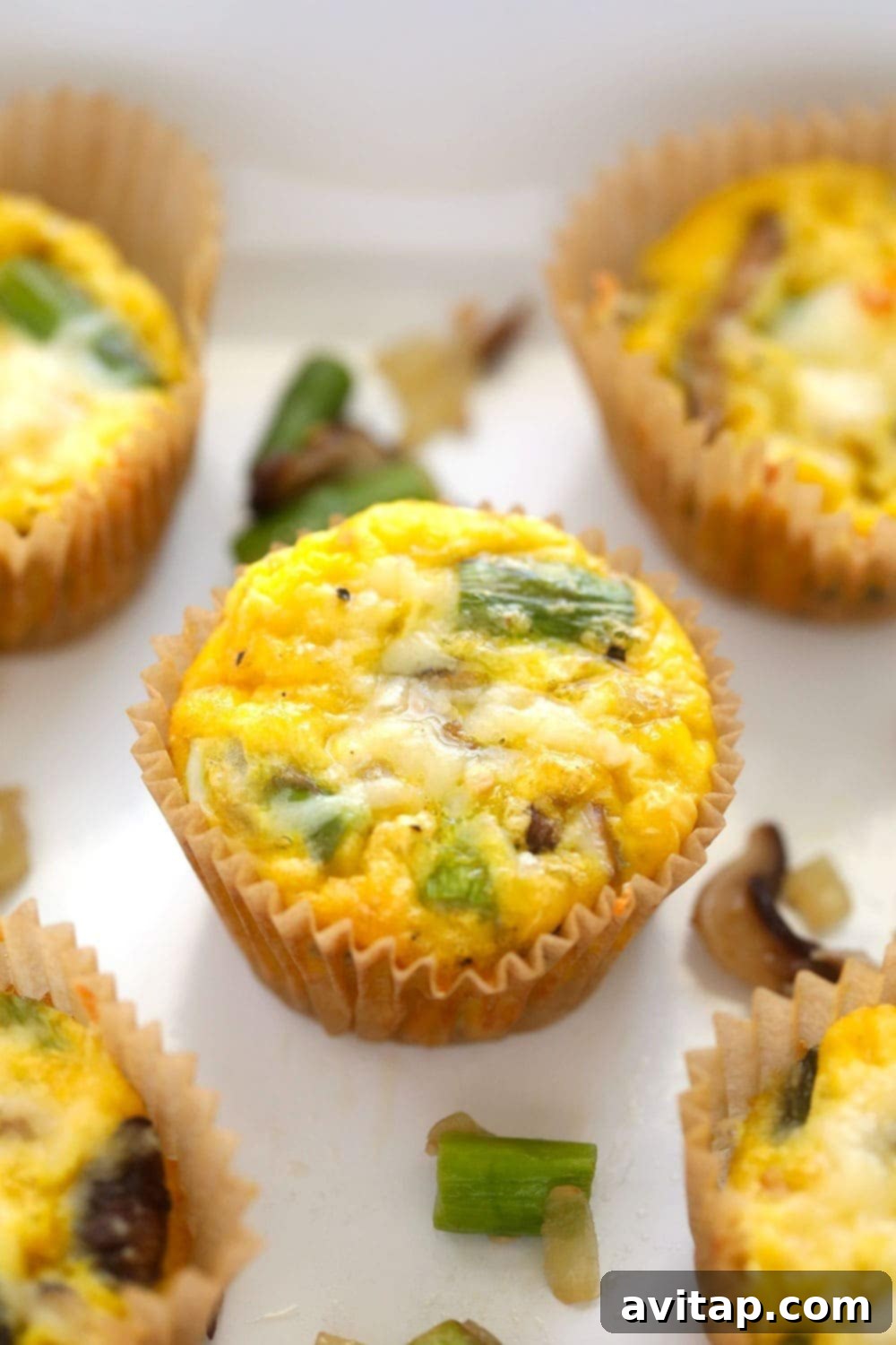 Enjoy these healthy and quick-to-make asparagus and mushroom egg cups, packed with 4 grams of protein. Close-up shot of freshly baked asparagus and mushroom egg cups, perfectly golden and ready to be enjoyed.