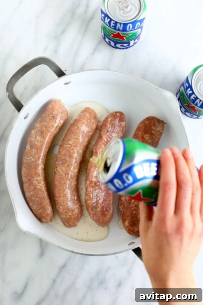 Uncooked brats submerged in a pot of beer on a stovetop, bubbling gently as they begin to cook.