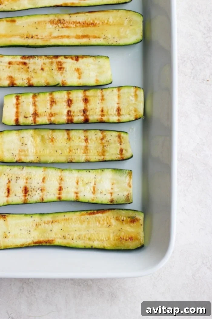 Beautifully arranged grilled zucchini slices in a baking dish, ready to be served or stored.