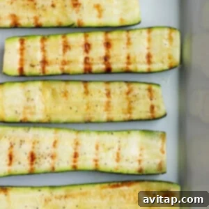 Grilled zucchini on platter, garnished with fresh herbs.