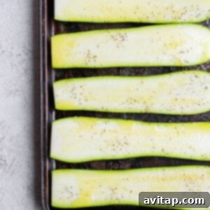 Sliced zucchini on a baking sheet, ready for seasoning.