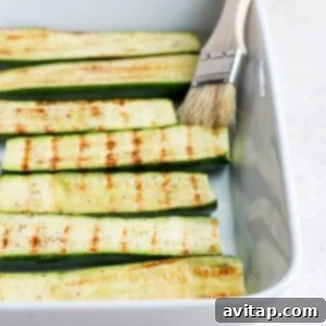 Cooked grilled zucchini arranged in a casserole dish, ready to serve.