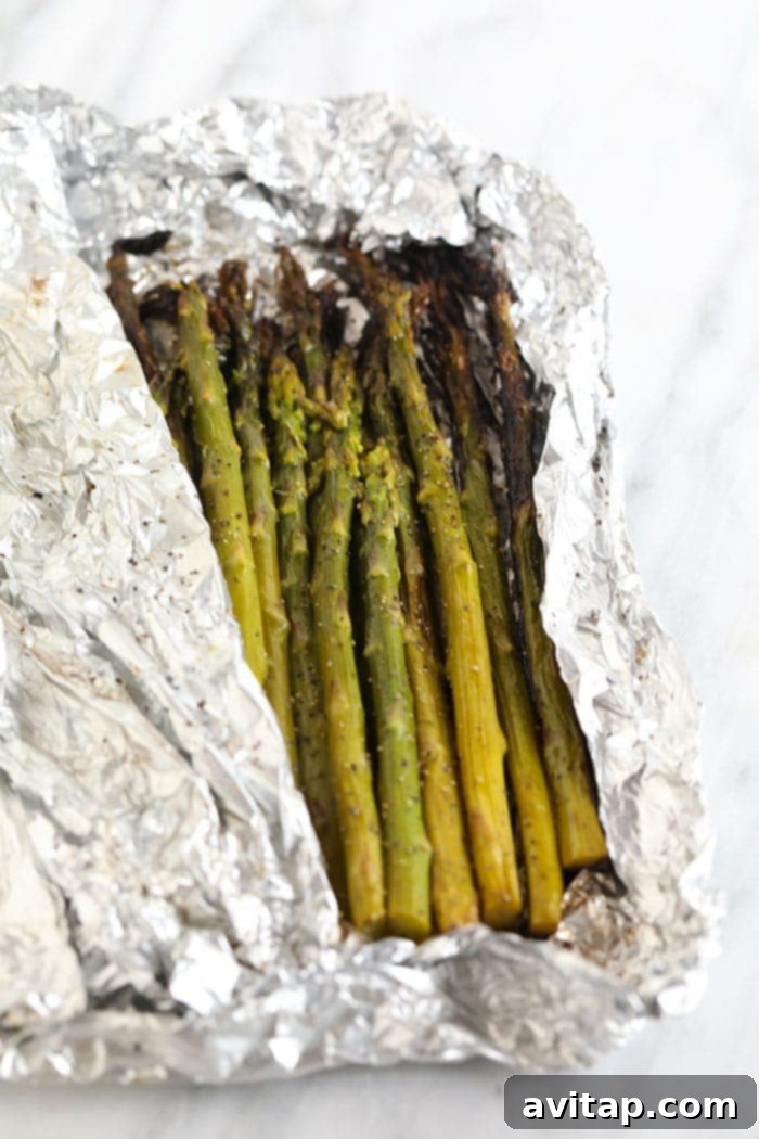 A freshly grilled foil pack of asparagus, slightly opened, showing the perfectly cooked green spears inside.