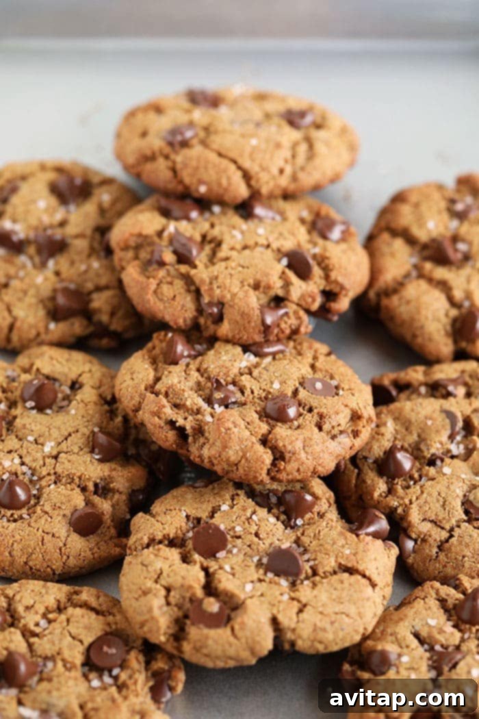 Healthy Chocolate Chip Cookies on Baking Sheet A close-up of healthy chocolate chip cookies on a baking sheet, highlighting the gooey chocolate and sea salt topping.