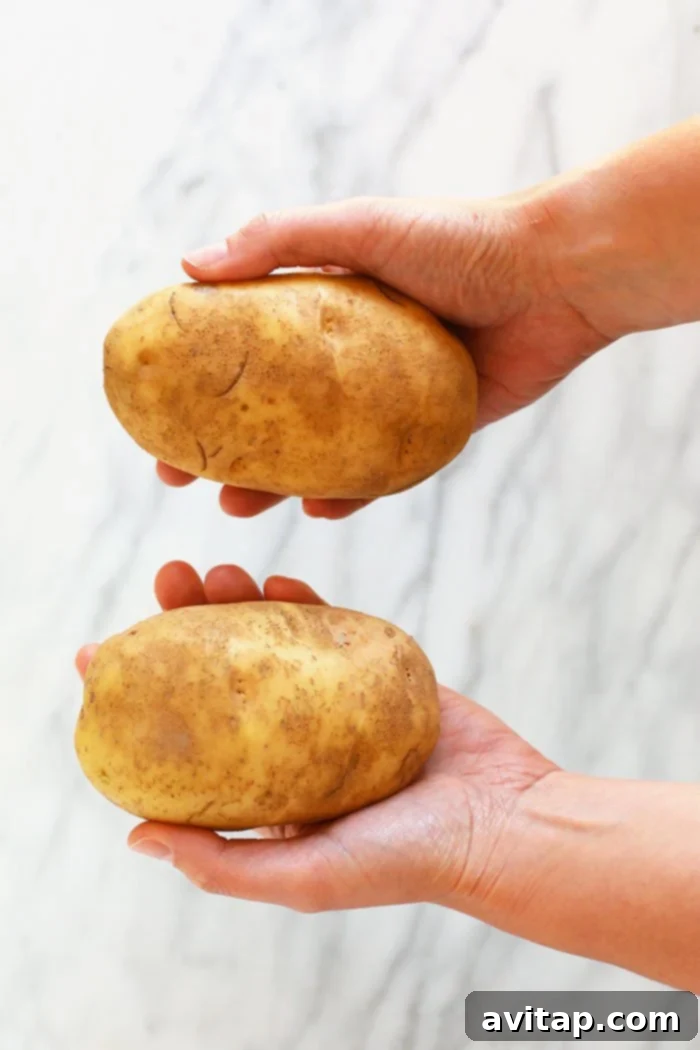 Foil-Wrapped Baked Potatoes 2 Hands carefully holding cleaned and prepared potatoes, ready for the next step in baking.