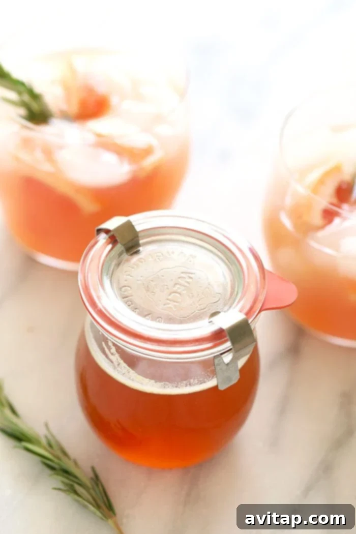 A beautifully presented jar of golden honey simple syrup with a wooden spoon, ready for use in drinks and recipes.
