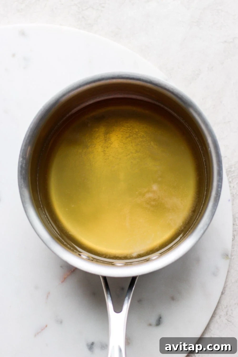 Close-up of a jar of raw honey and a glass of water, illustrating the two simple ingredients needed for honey simple syrup.
