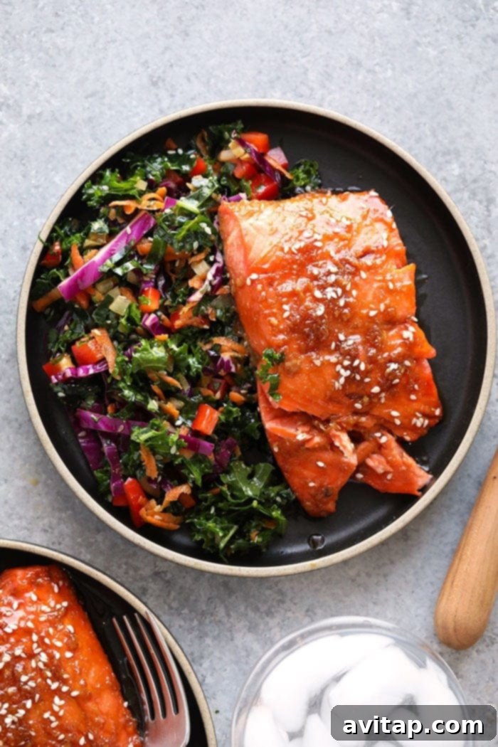 Delicious Maple Ginger Baked Salmon on a white plate with fresh herbs, showcasing its flaky texture and golden glaze.