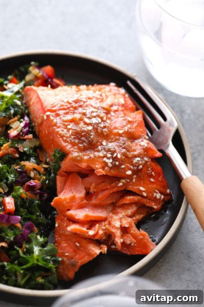 Close-up of a perfectly cooked Maple Ginger Baked Salmon fillet on a plate, garnished with fresh herbs, ready to be served.