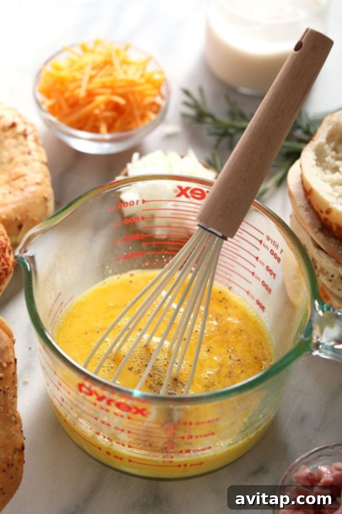 Fresh eggs being whisked in a clear glass mixing bowl, ready for the quiche mixture