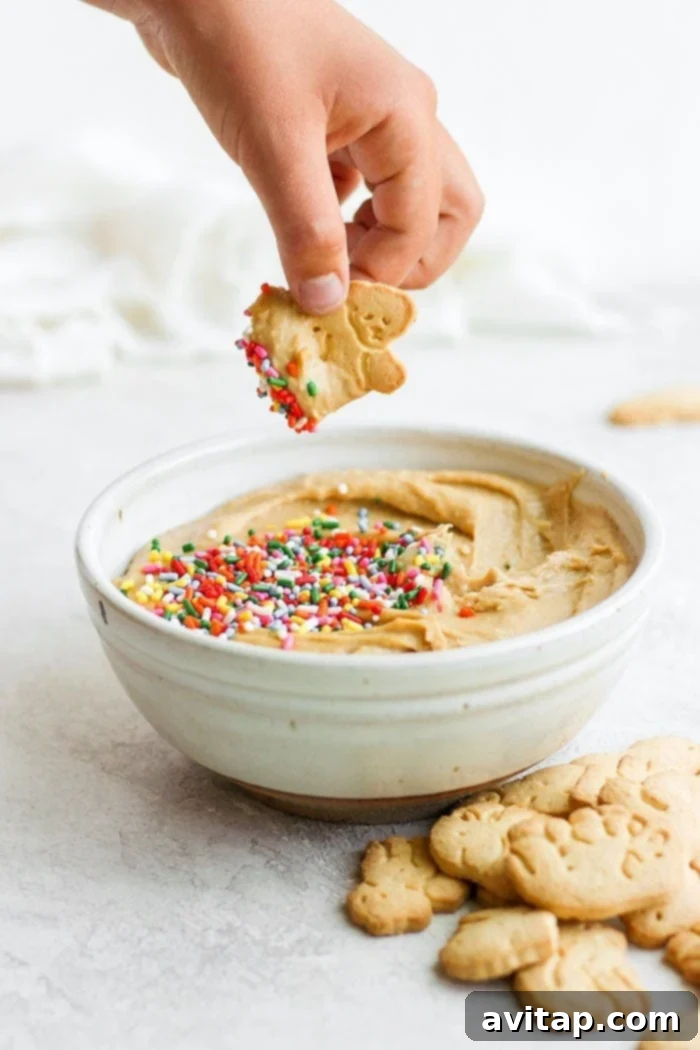 Animal crackers being dipped into a bowl of funfetti cake batter dip