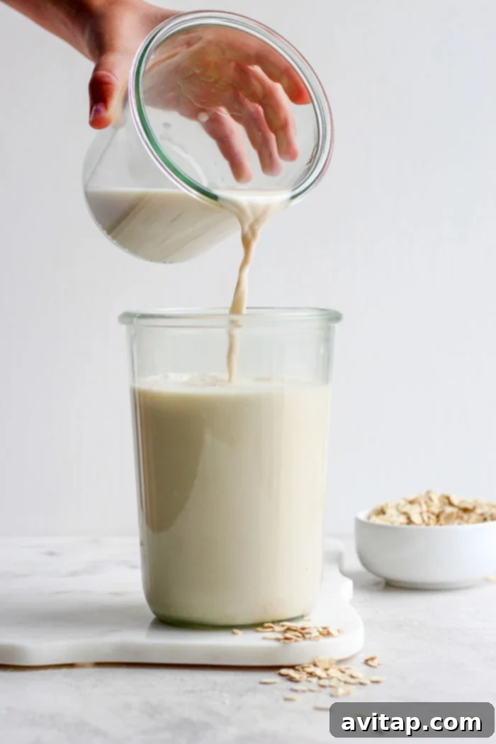 Pouring homemade oat milk into a glass