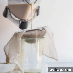 Sieving freshly blended oat milk into a jar.