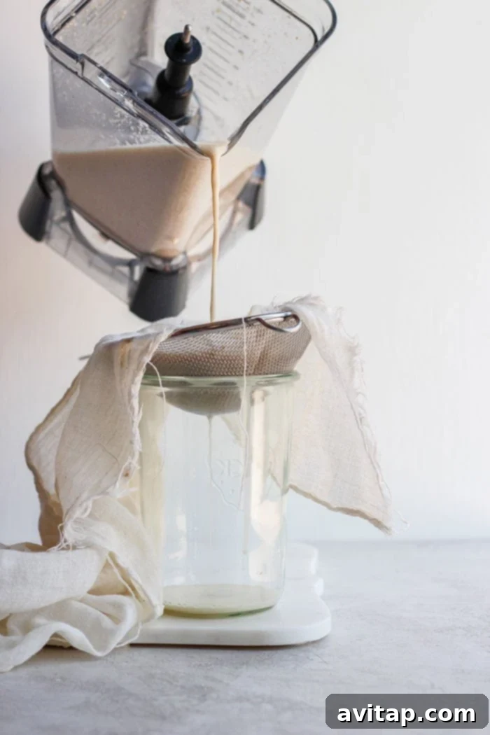 Pouring freshly blended oat milk into a tea towel for straining