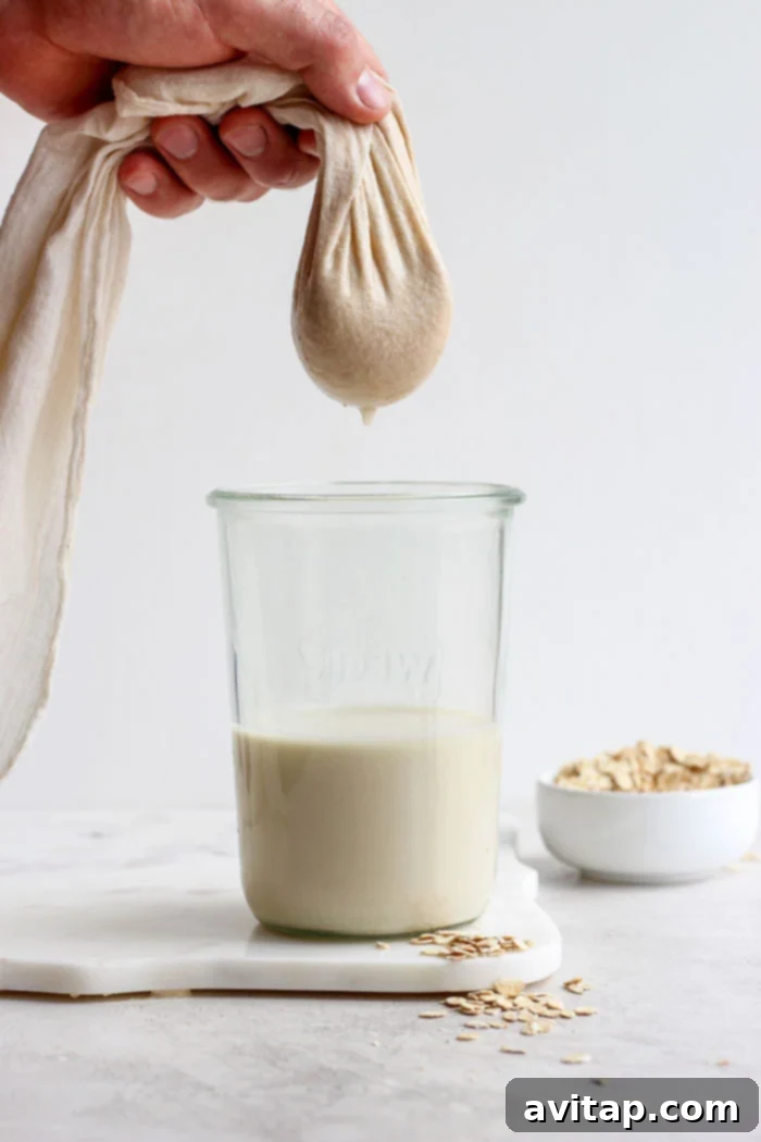 Filtering out oat milk through a tea towel into a pitcher