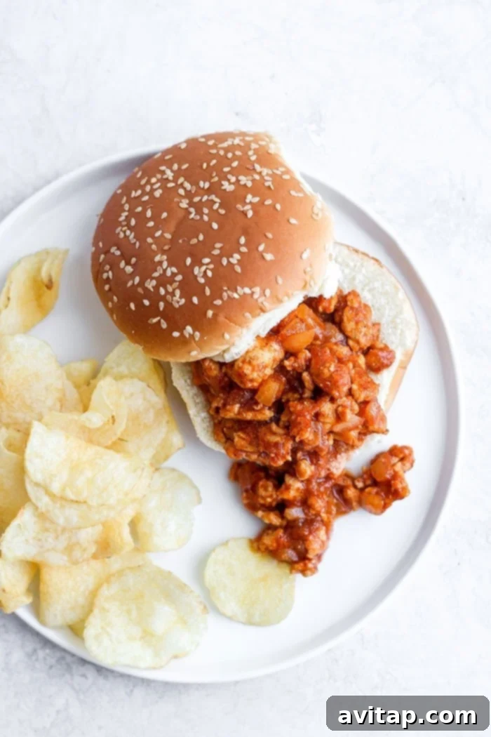 The perfectly savory and sweet Healthy Sloppy Joe Recipe is here! Made with ground chicken and a flavorful sauce packed with clean ingredients, these Sloppy Joes will not disappoint! Healthy sloppy joe on a bun with chips, a delightful and complete meal