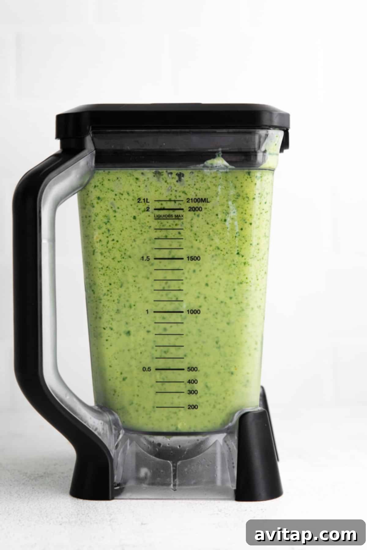 A freshly blended tropical spinach smoothie poured into a glass, garnished with fresh fruit, emphasizing its appealing green color and smooth texture.