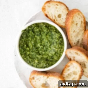 A small bowl filled with vibrant green homemade pesto, ready to be used in pasta dishes.