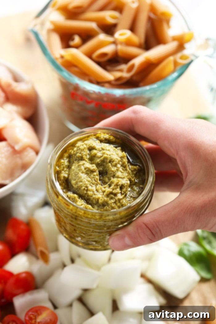Freshly made green pesto stored in a glass jar, ready for use in various dishes.