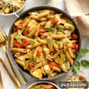 A delicious bowl of chicken pesto pasta, garnished with fresh basil.