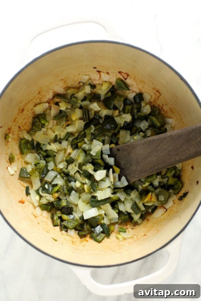 Green Chili (AKA Chile Verde) never looked so good! This easy green chicken chili is made with roasted peppers, your favorite salsa verde, chicken breast, and white beans. Diced green peppers, onions, and garlic simmering in a stockpot, forming the aromatic base of the green chili.