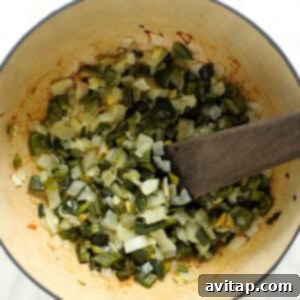 A pot filled with green chili vegetables and a wooden spoon.