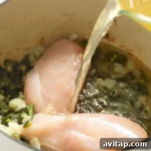Chicken breasts being poured into a pan with green chili.