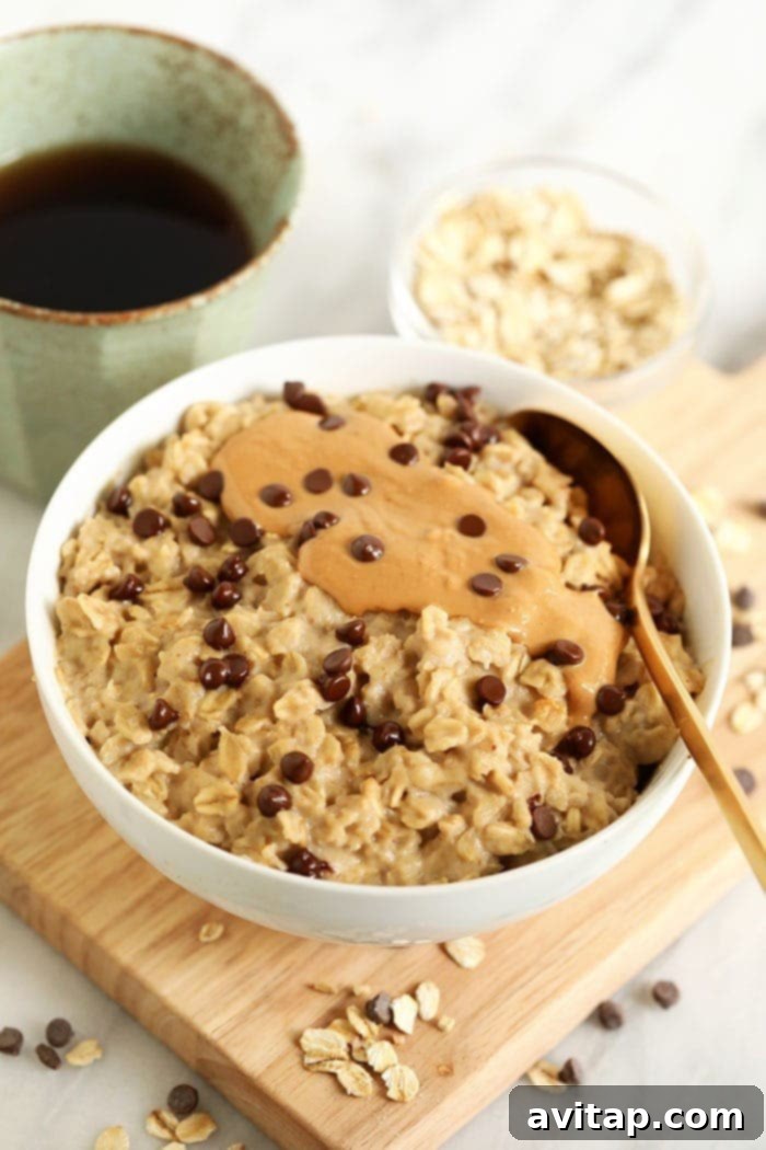 A close-up shot of creamy oatmeal in a bowl, generously topped with smooth cashew butter and decadent chocolate chips, mimicking cookie dough.