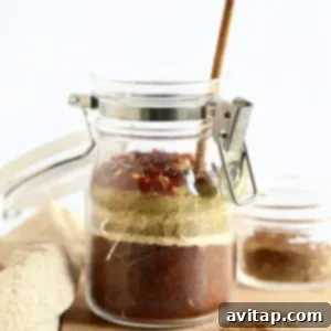 A homemade taco seasoning mix in a glass jar with a small wooden spoon, ready for long-term storage.