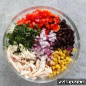 Shredded chicken and vegetables in a bowl before dressing.