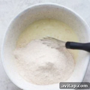 Combining wet and dry ingredients in a bowl to make pancake batter.