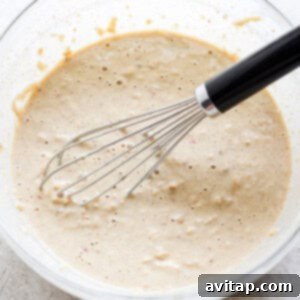 A bowl of pancake batter with a whisk, showing the consistency of the mixture.