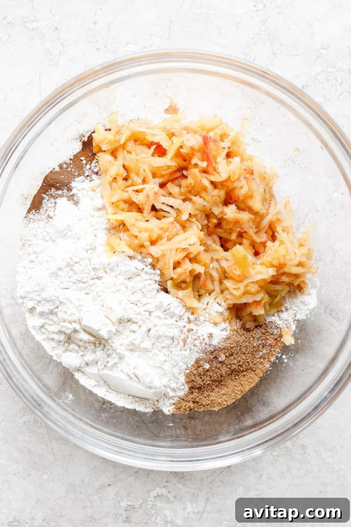 A mixing bowl filled with dry ingredients like flour, cinnamon, and coconut sugar, ready for wet ingredients.