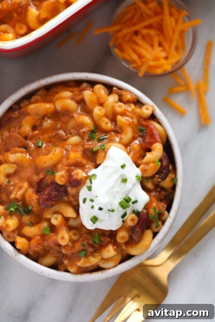Chili mac and cheese might be the best dinner of all time. Make it once and eat it all week long. Bonus, it's kid-friendly and protein-packed! Chili mac in a bowl with greek yogurt scooped on top